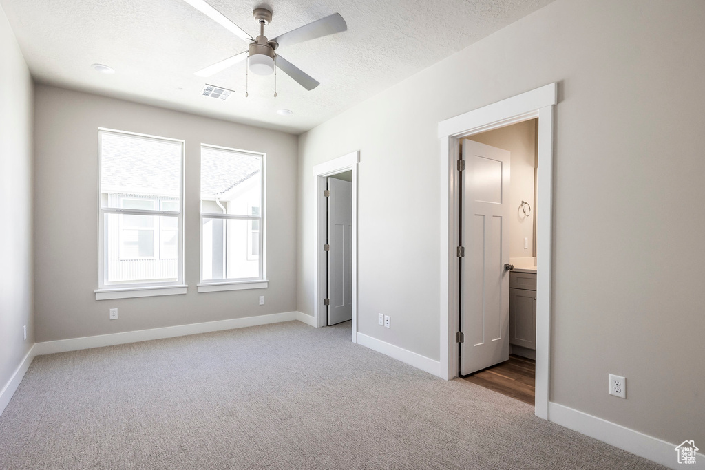 Unfurnished bedroom with light colored carpet, ceiling fan, and ensuite bathroom