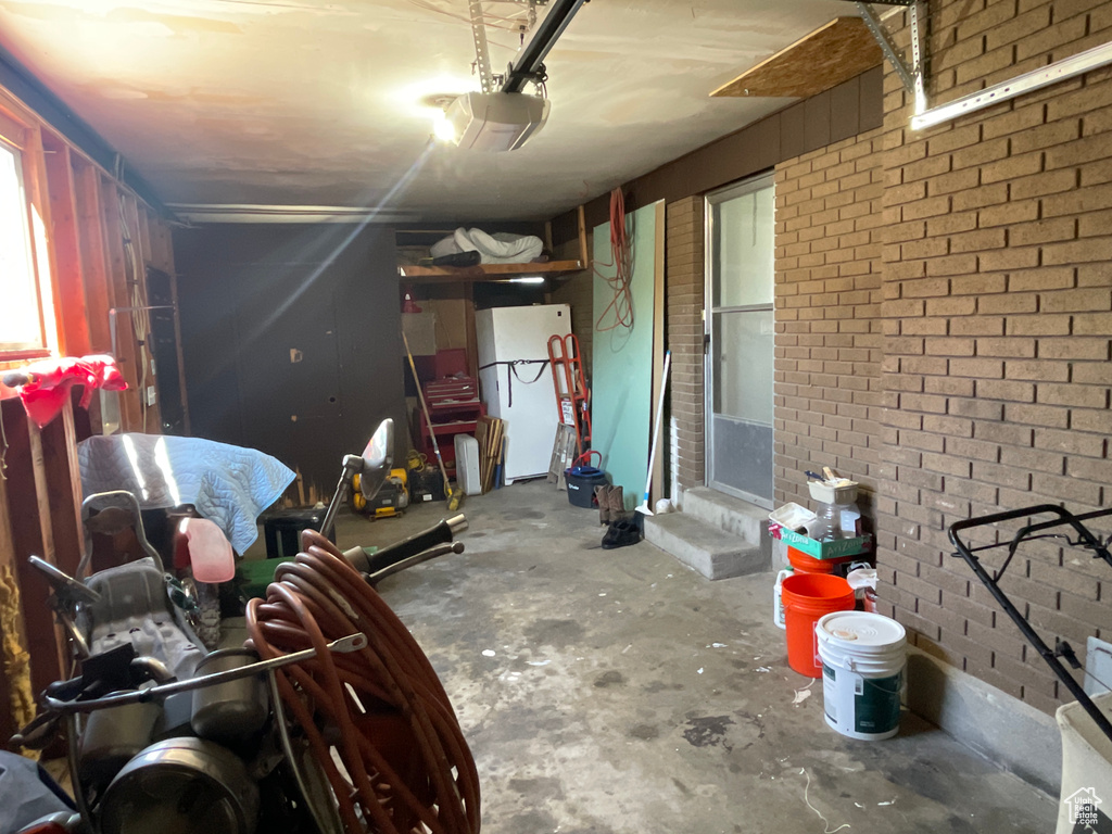 Garage featuring a garage door opener and white fridge