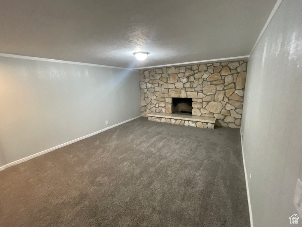 Unfurnished living room with crown molding, carpet flooring, a textured ceiling, and a fireplace