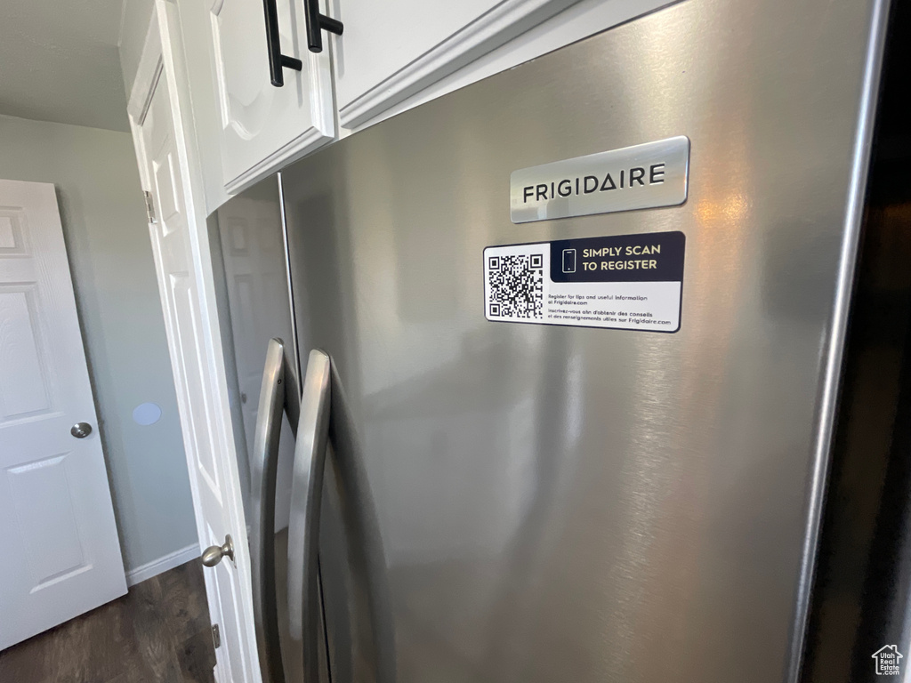 Details with dark hardwood / wood-style floors, stainless steel fridge, and white cabinets