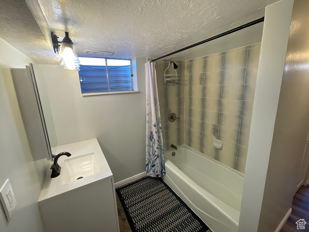 Bathroom featuring a textured ceiling, vanity, hardwood / wood-style floors, and shower / bath combination with curtain