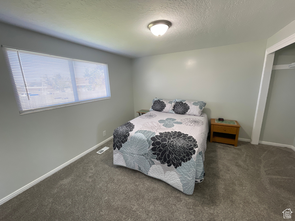 Bedroom with a textured ceiling and carpet