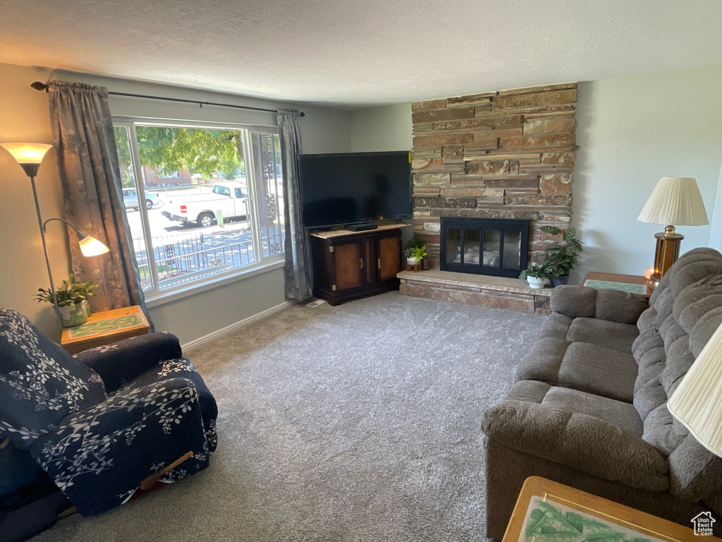 Carpeted living room featuring a textured ceiling and a stone fireplace