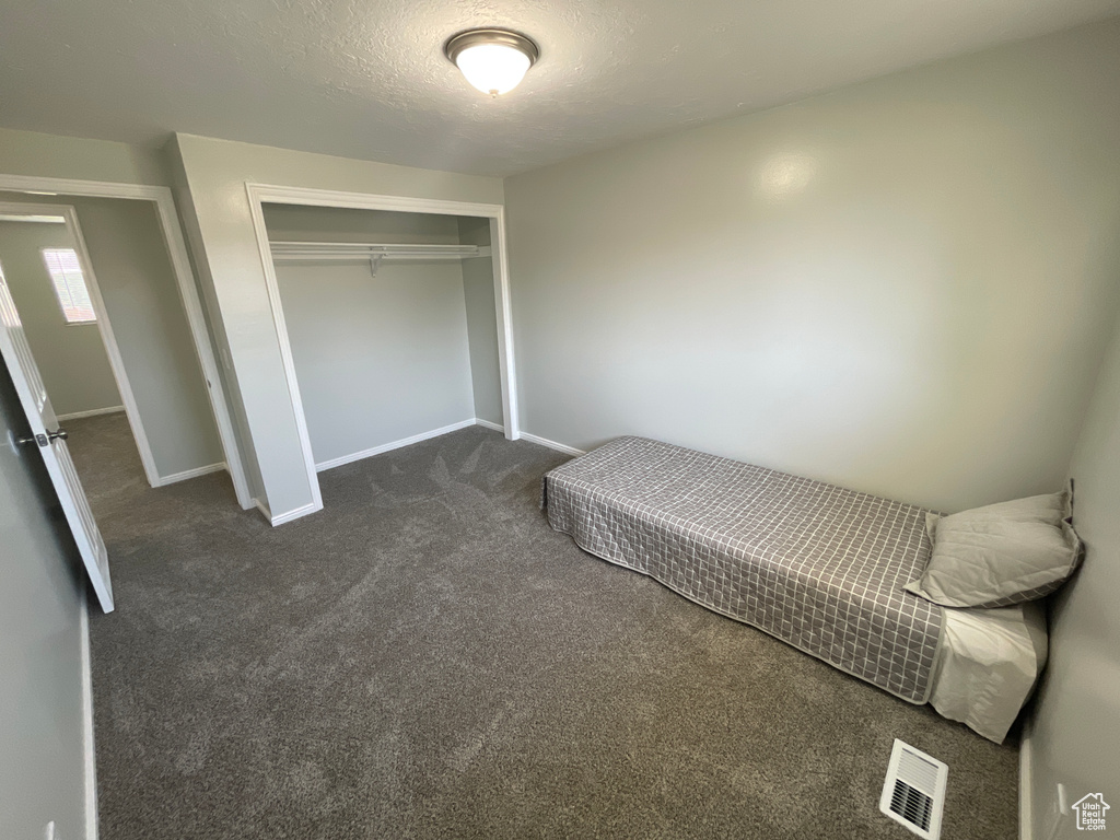 Carpeted bedroom featuring a closet and a textured ceiling