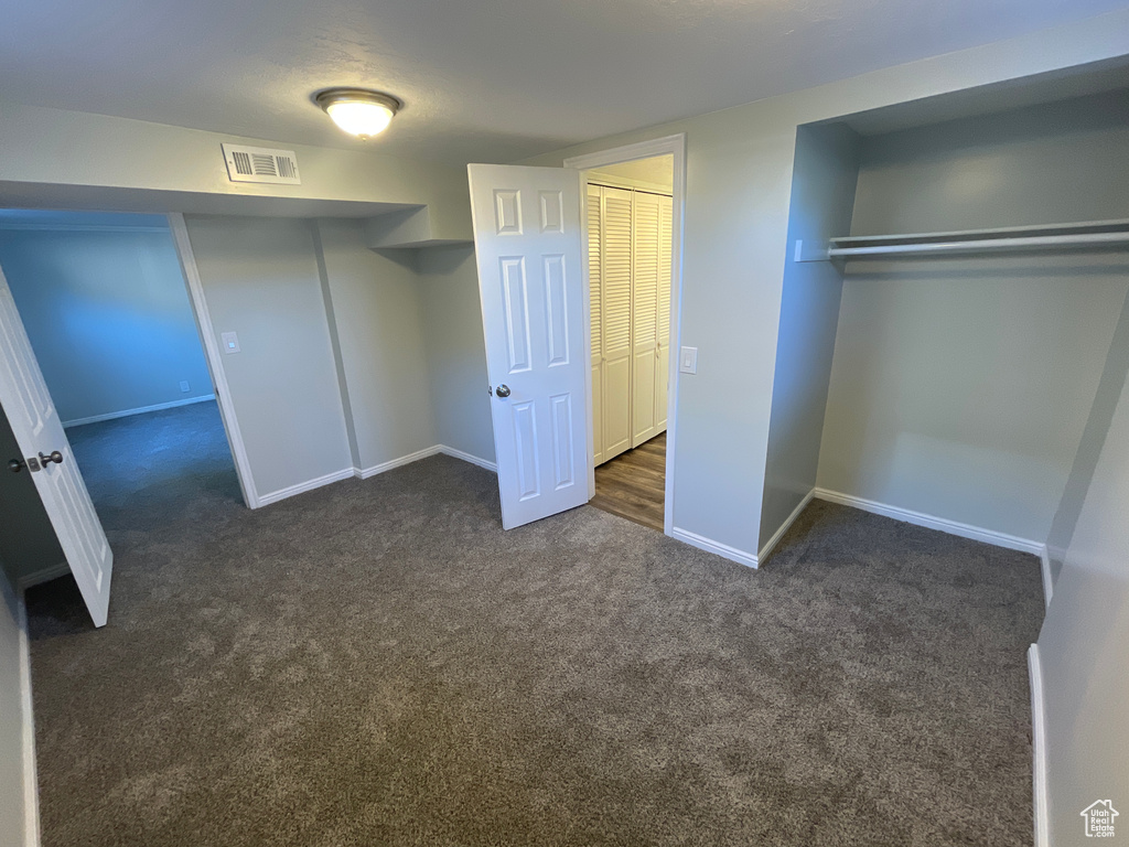 Unfurnished bedroom with dark carpet