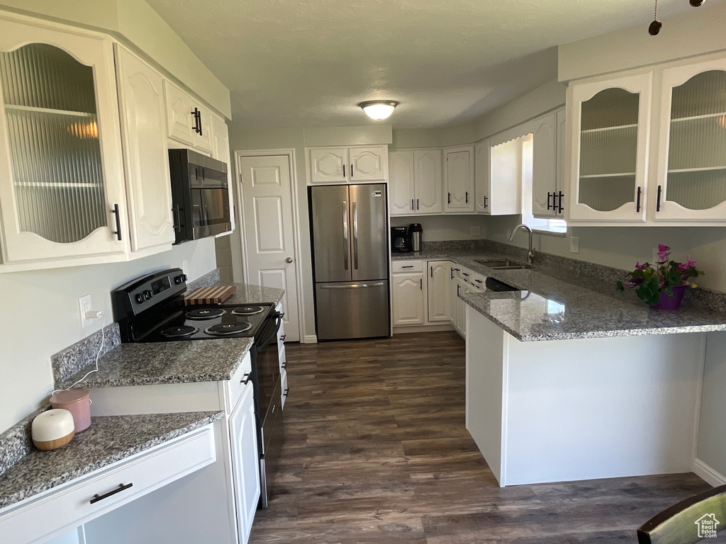 Kitchen with stone counters, stainless steel appliances, white cabinetry, sink, and dark hardwood / wood-style floors