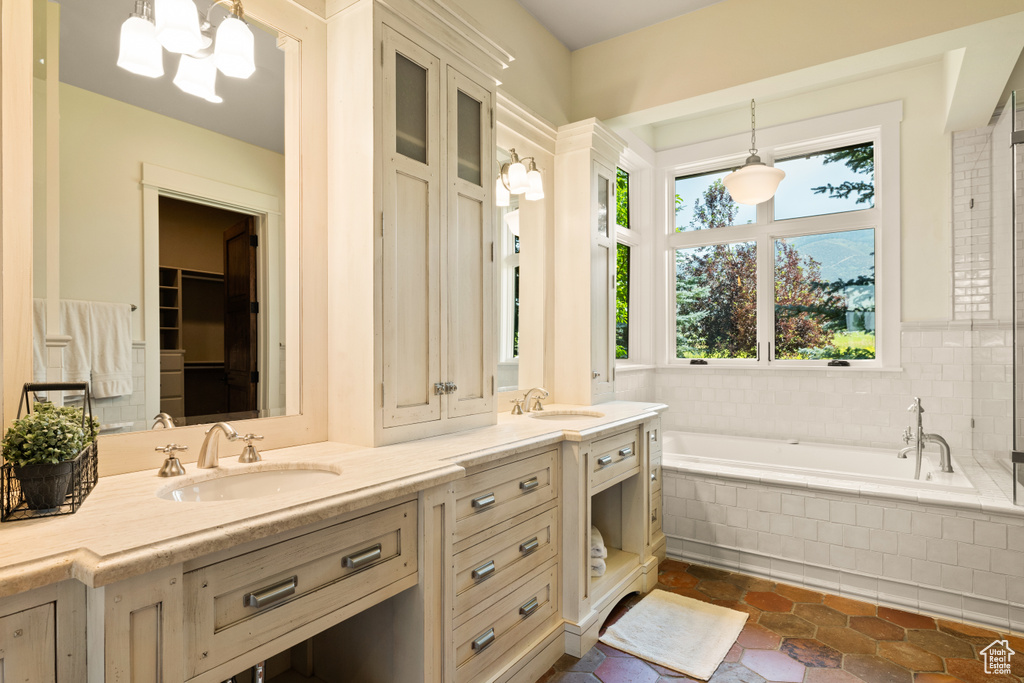 Bathroom with tile patterned flooring, vanity, and a relaxing tiled tub