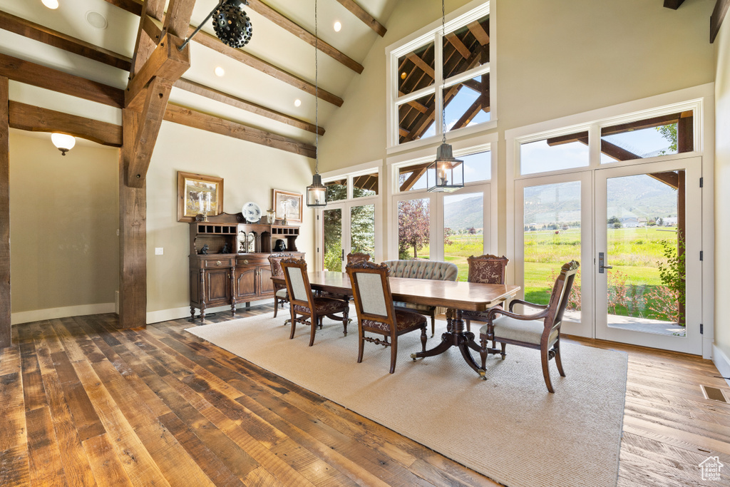 Dining area with hardwood / wood-style floors, a wealth of natural light, and beamed ceiling