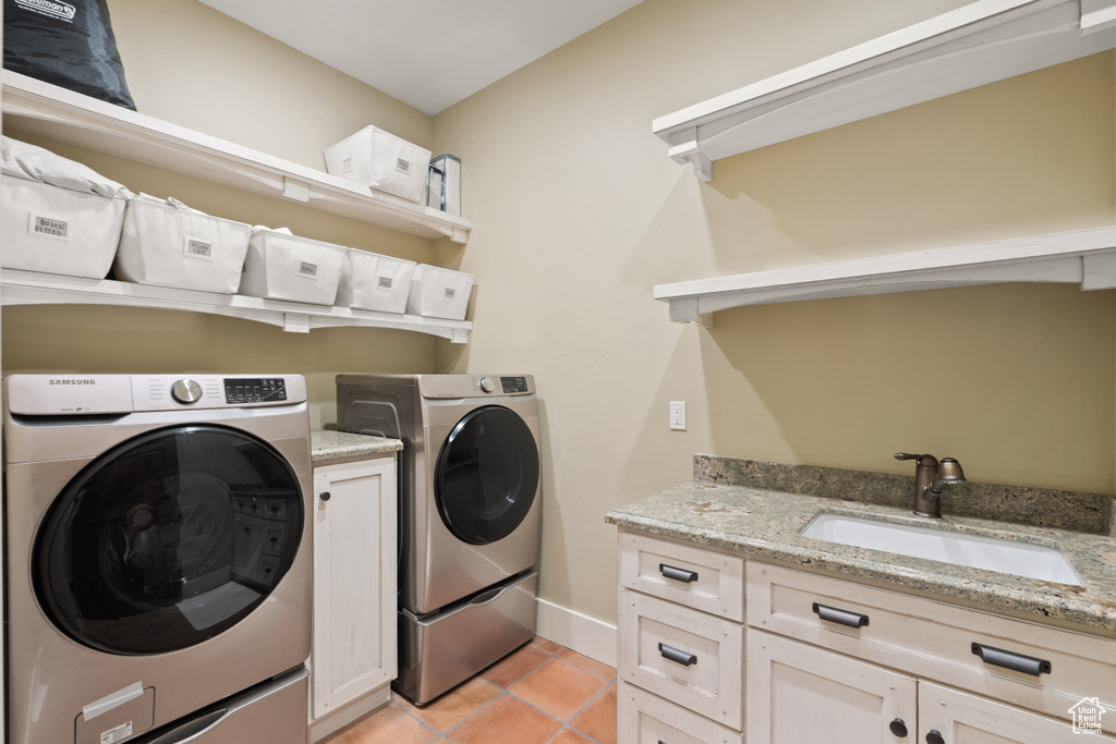 Washroom with cabinets, washer and clothes dryer, sink, and light tile patterned floors