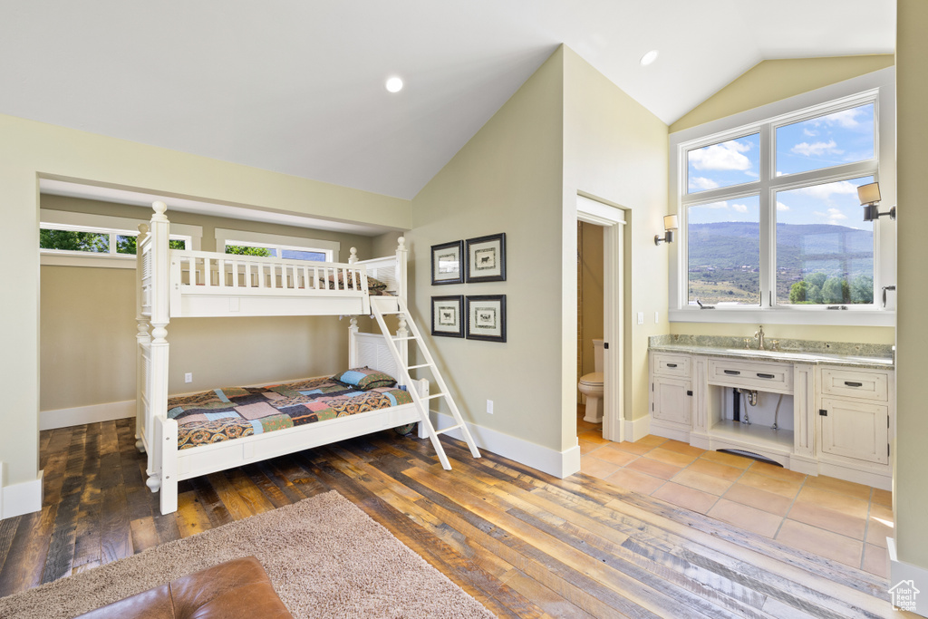 Bedroom featuring ensuite bath, hardwood / wood-style floors, lofted ceiling, and a mountain view