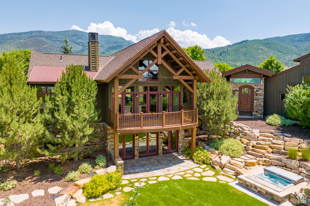 Back of house with a mountain view and an in ground hot tub