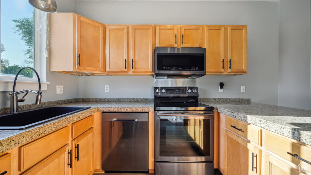 Kitchen with sink, light brown cabinets, and appliances with stainless steel finishes