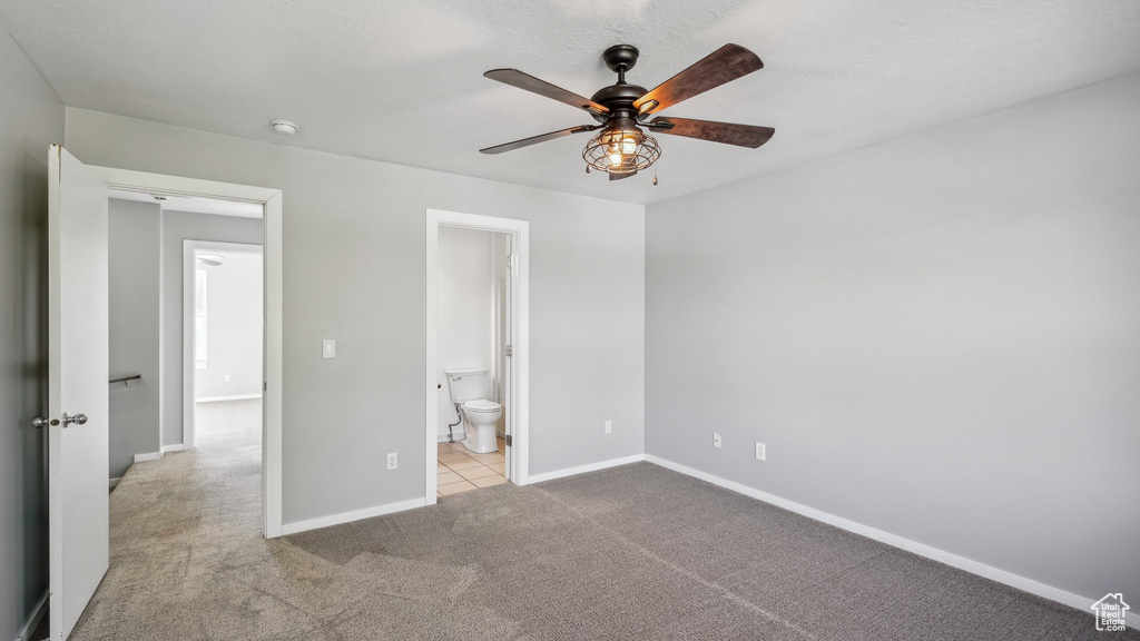 Unfurnished bedroom with light colored carpet, ceiling fan, and ensuite bathroom