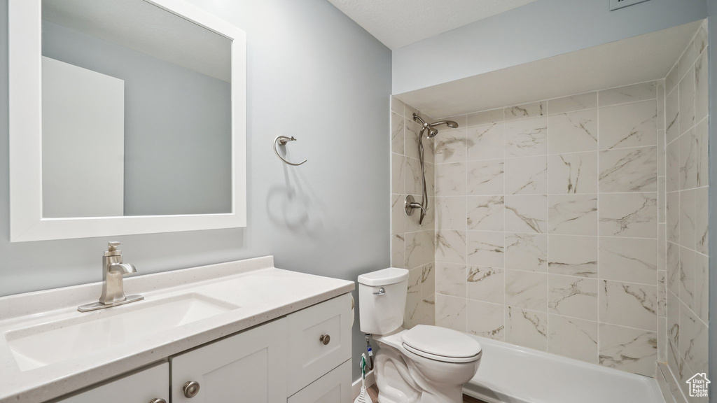 Bathroom with tiled shower, toilet, and vanity