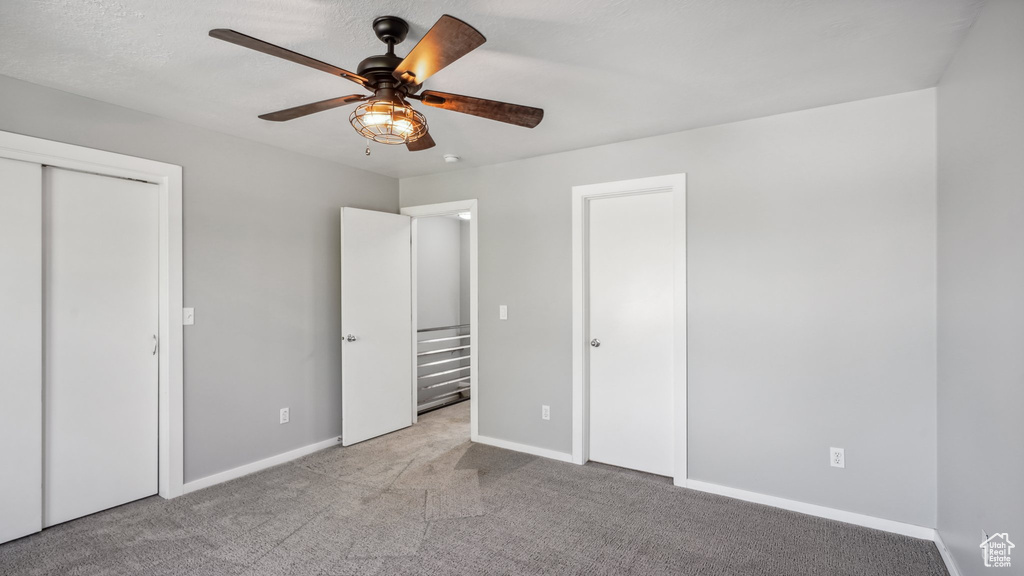 Unfurnished bedroom with light colored carpet and ceiling fan