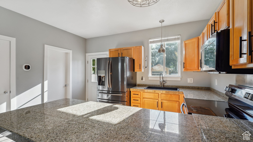 Kitchen with hanging light fixtures, stainless steel appliances, and sink