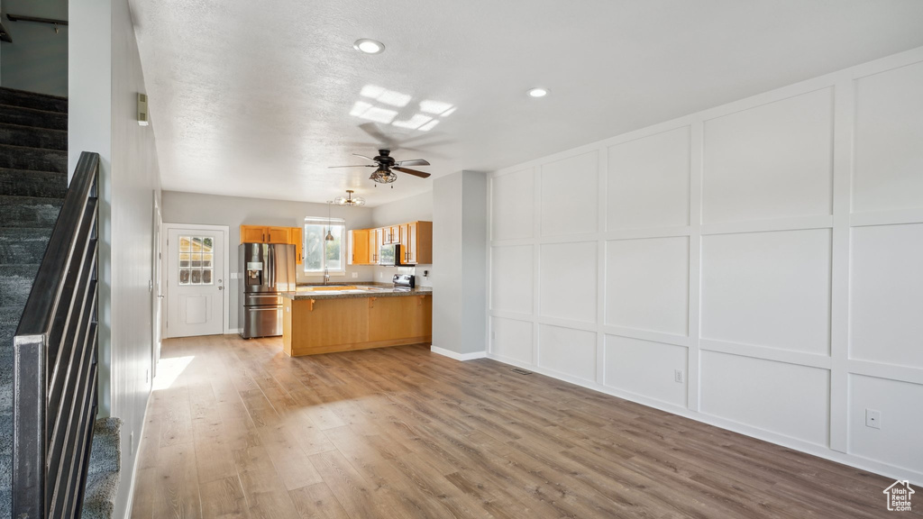 Kitchen featuring ceiling fan, sink, stainless steel fridge, and light hardwood / wood-style floors