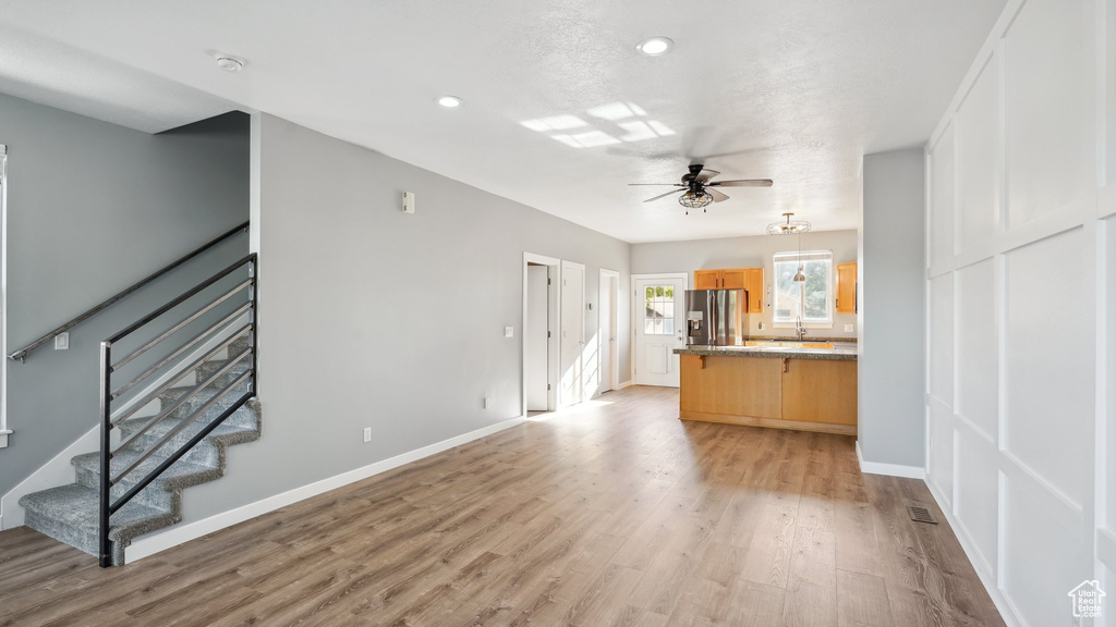 Unfurnished living room featuring ceiling fan and light hardwood / wood-style floors