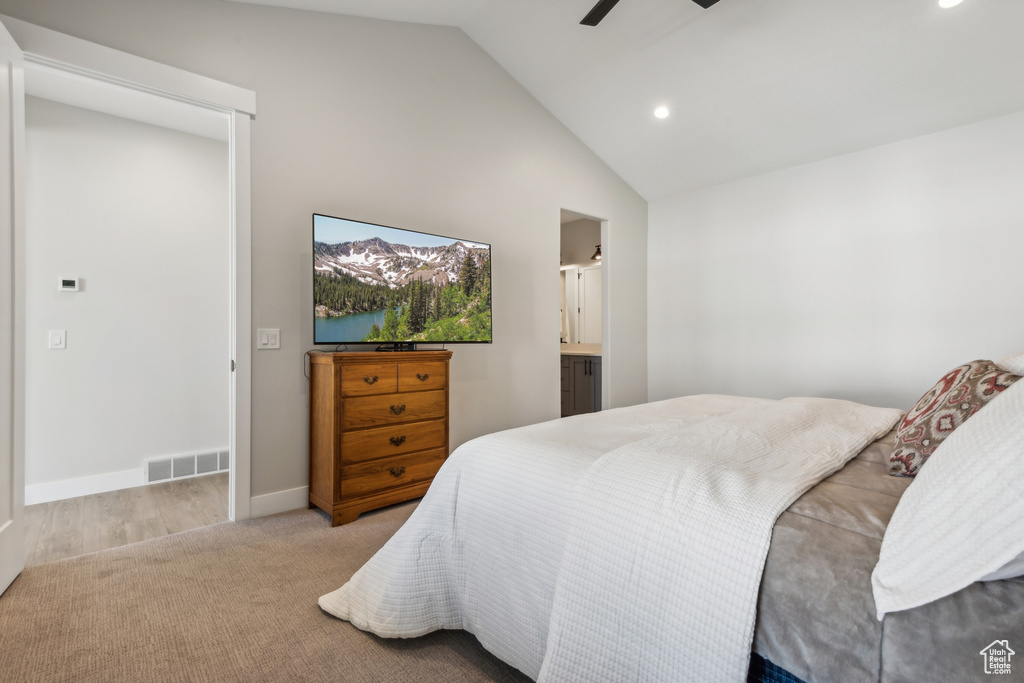 Bedroom featuring ensuite bath, lofted ceiling, light colored carpet, and ceiling fan