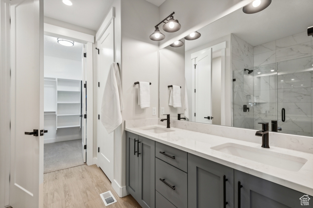 Bathroom featuring a shower with door, vanity, and wood-type flooring