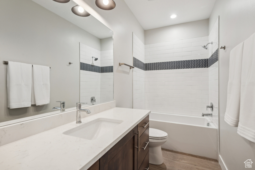 Full bathroom featuring tiled shower / bath, vanity, toilet, and wood-type flooring