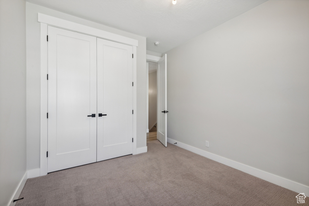 Unfurnished bedroom with a closet and light carpet