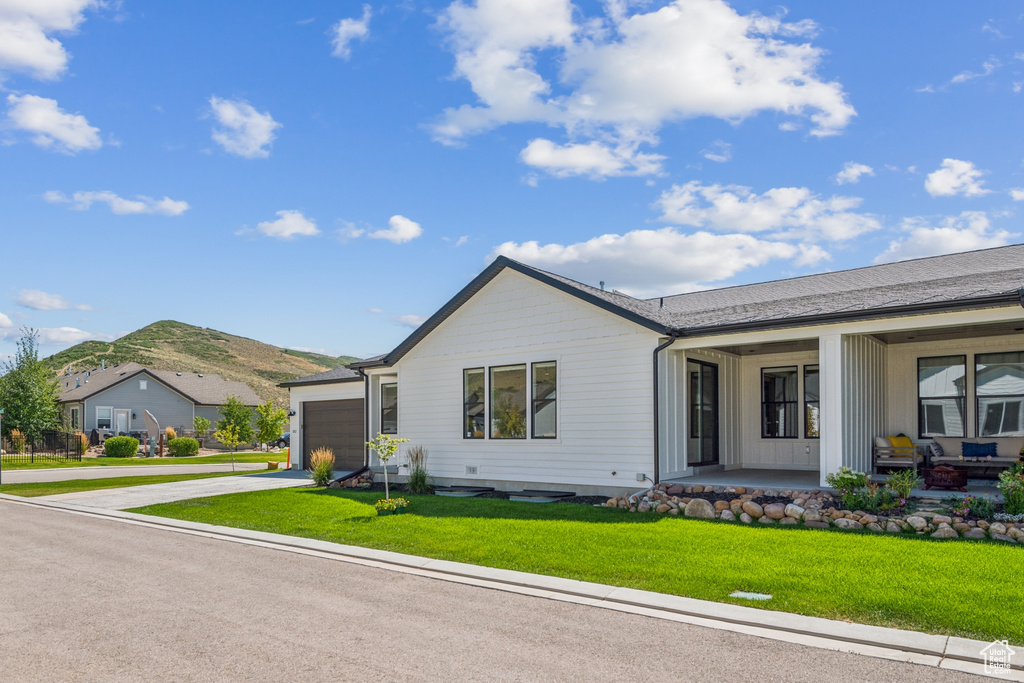 Single story home with a porch, a garage, and a front lawn