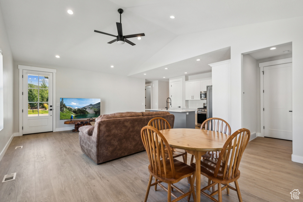 Dining room with light wood-type flooring, vaulted ceiling, sink, and ceiling fan