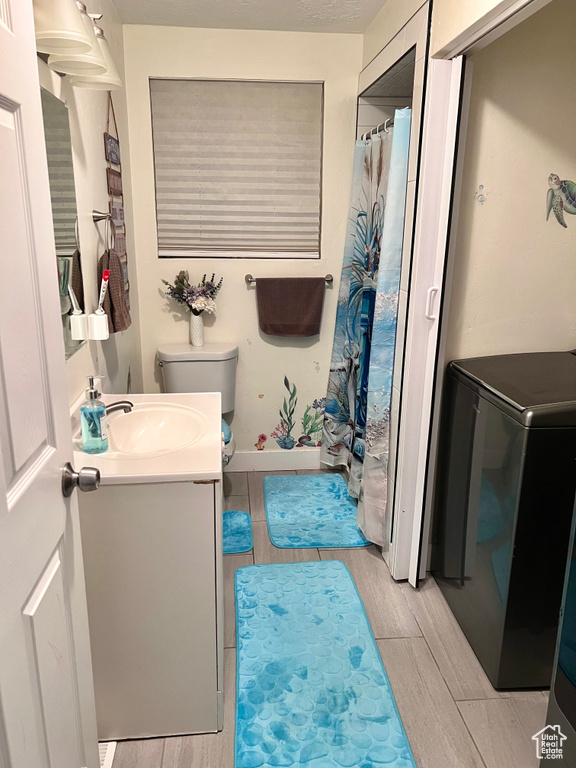 Bathroom featuring toilet, a shower with curtain, vanity, and wood finished floors