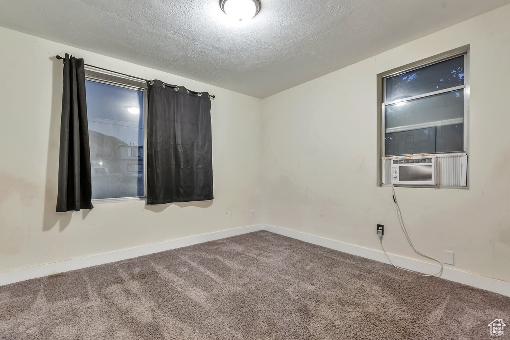 Carpeted empty room featuring cooling unit and a textured ceiling