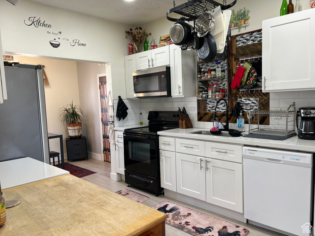 Kitchen featuring decorative backsplash, light countertops, a sink, and appliances with stainless steel finishes