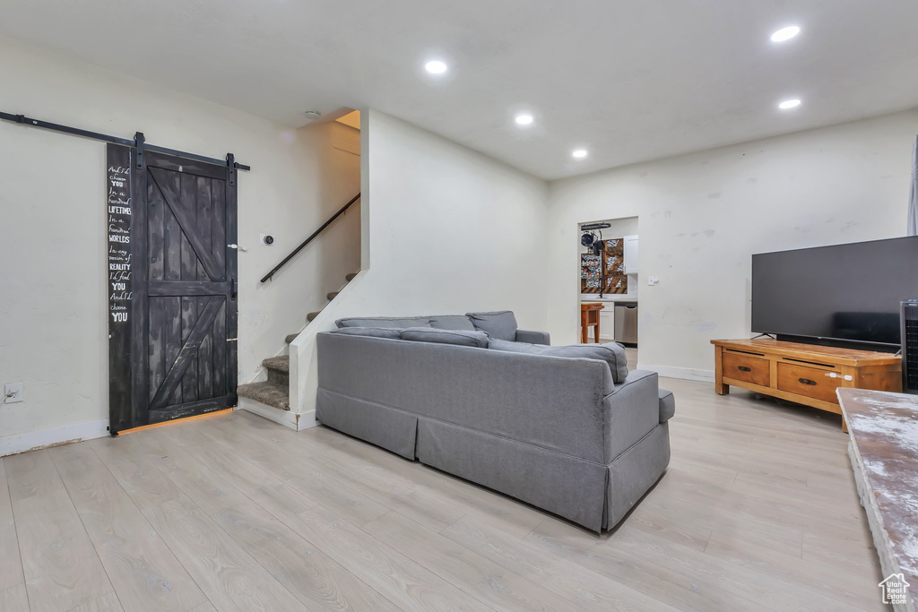 Living room with a barn door and light hardwood / wood-style floors
