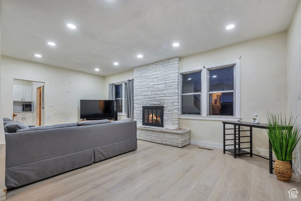 Living room with a fireplace and light wood-type flooring