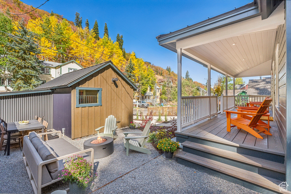 View of patio / terrace featuring a fire pit, a wooden deck, and a storage unit