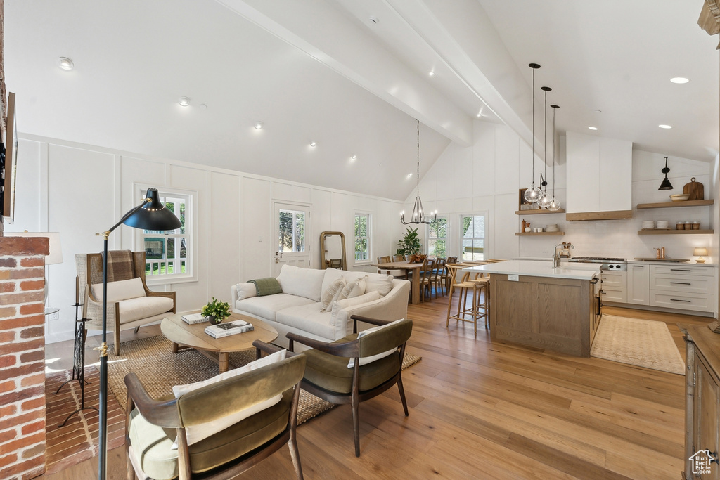 Living room featuring high vaulted ceiling, a healthy amount of sunlight, beam ceiling, and light hardwood / wood-style flooring