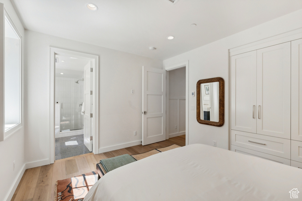 Bedroom with light hardwood / wood-style flooring and ensuite bath