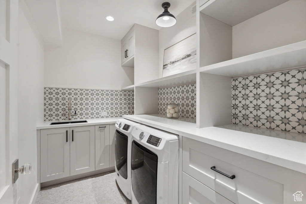 Washroom with washing machine and dryer, sink, and cabinets