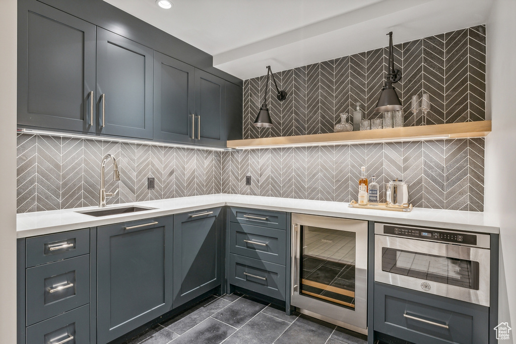 Kitchen with decorative backsplash, wine cooler, sink, and dark tile patterned flooring