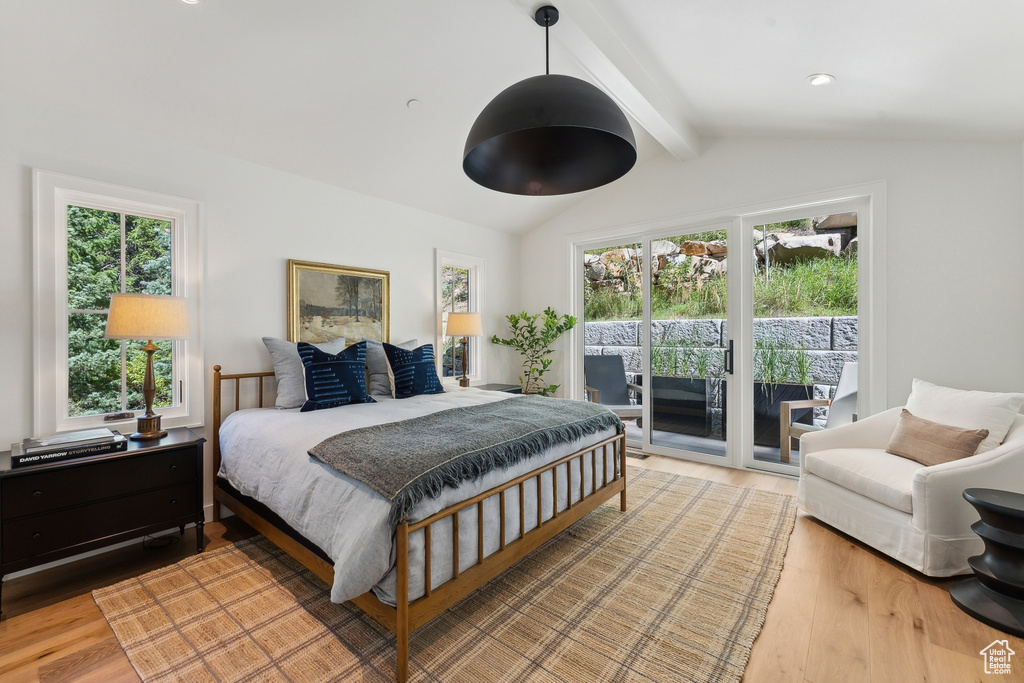 Bedroom with lofted ceiling with beams, access to exterior, and wood-type flooring