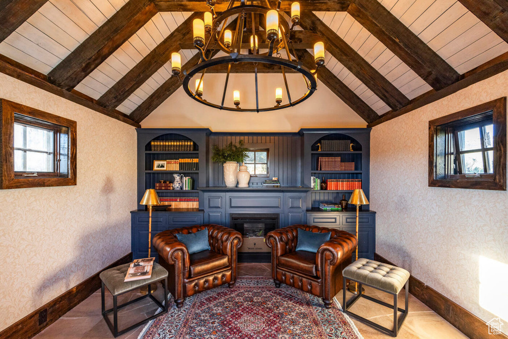 Living area featuring lofted ceiling with beams, plenty of natural light, a chandelier, and built in shelves