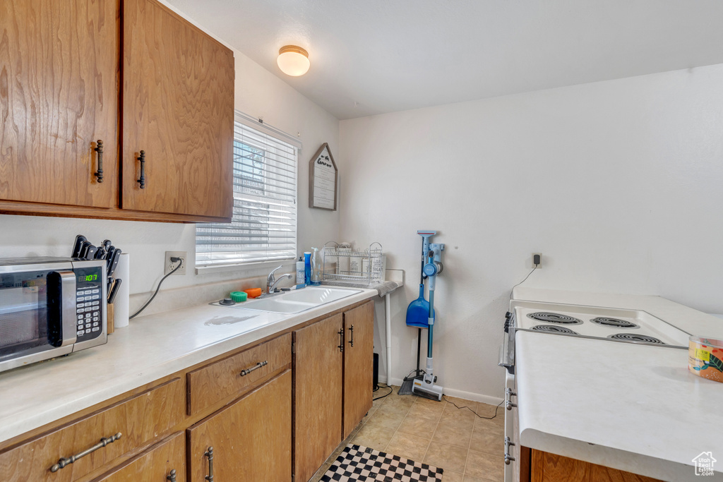 Kitchen featuring light tile patterned floors, sink, and electric stove