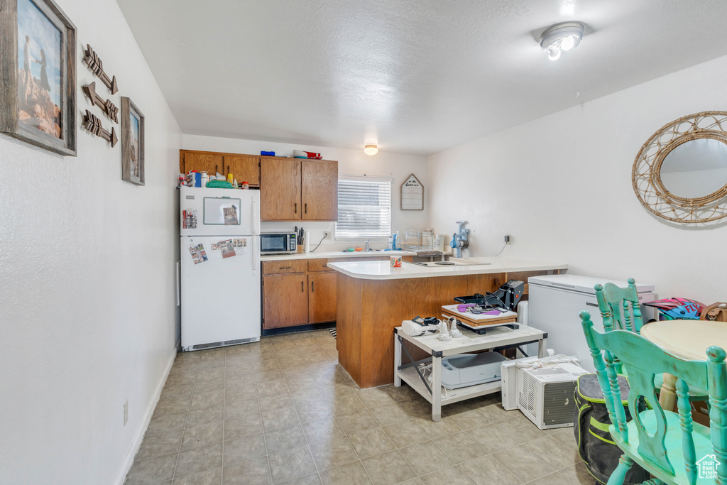 Kitchen featuring white refrigerator and kitchen peninsula