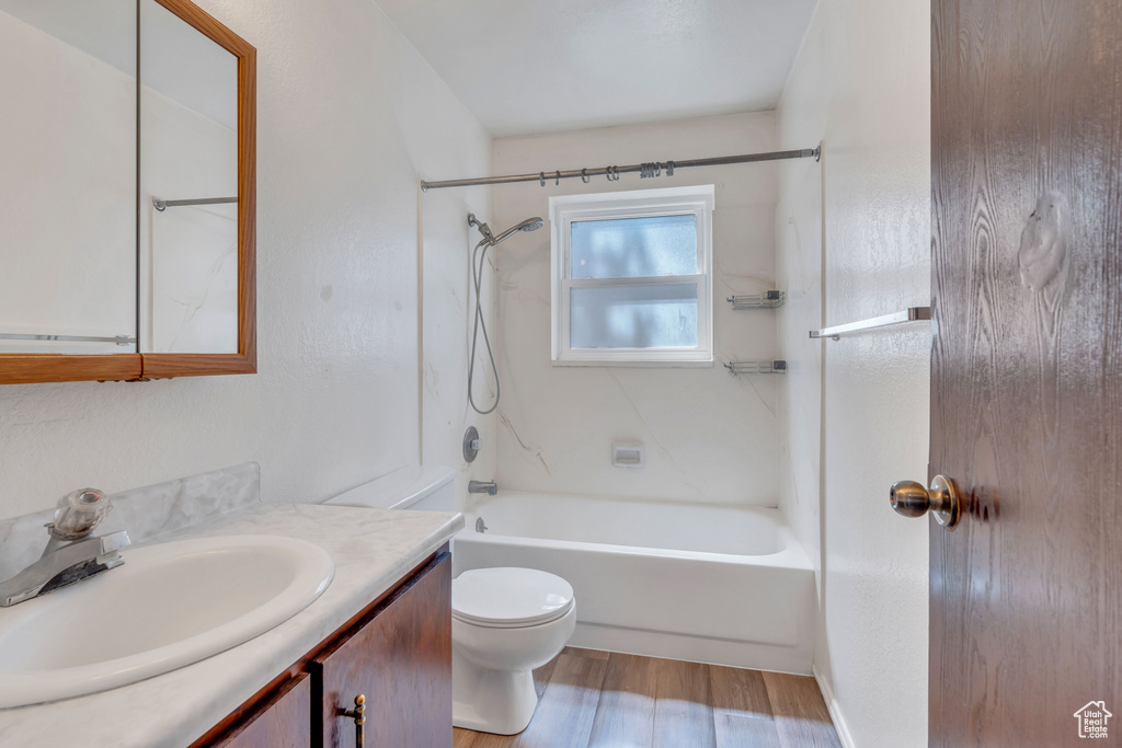 Full bathroom featuring hardwood / wood-style floors, toilet,  shower combination, and vanity