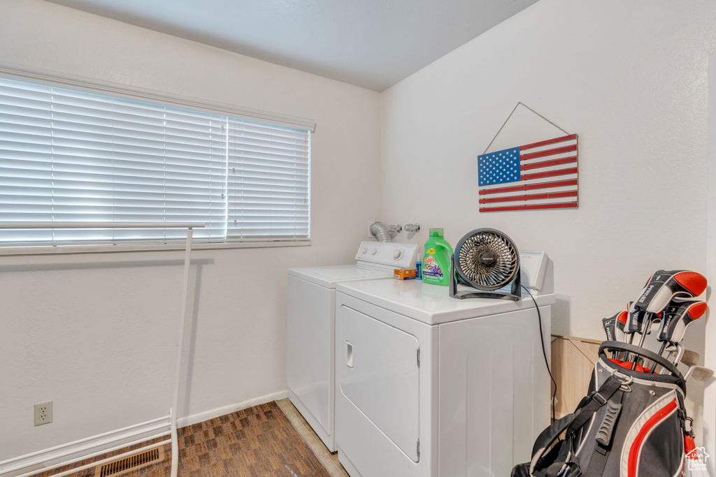 Laundry room with hardwood / wood-style flooring and washing machine and dryer