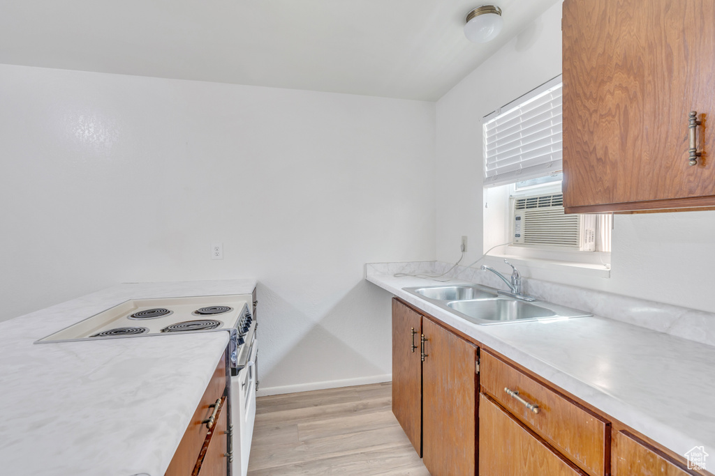 Kitchen featuring light hardwood / wood-style flooring, cooling unit, white range with electric stovetop, and sink