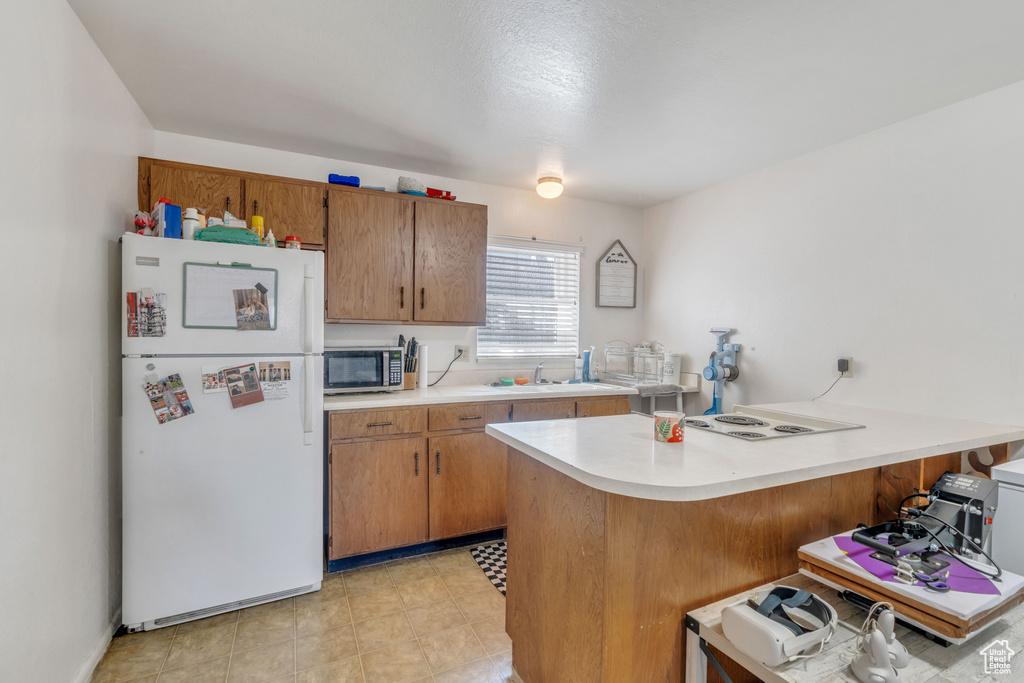 Kitchen featuring a kitchen bar, kitchen peninsula, white fridge, and sink