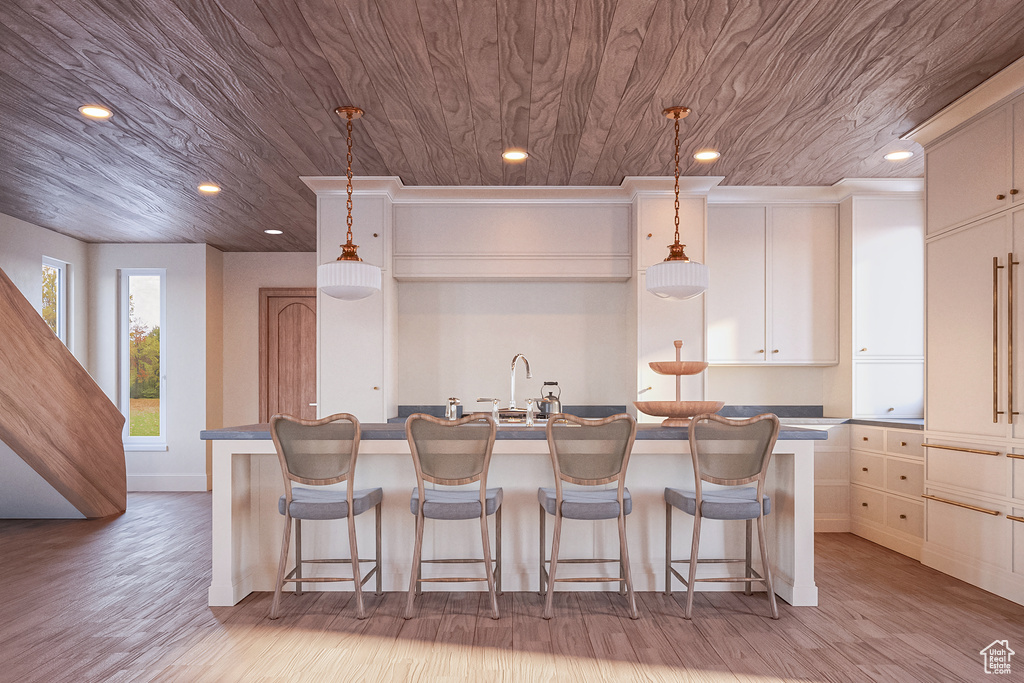 Kitchen featuring decorative light fixtures, an island with sink, and a breakfast bar