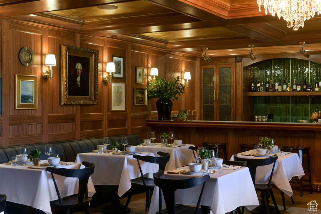 Dining space featuring a notable chandelier, wooden walls, and beamed ceiling