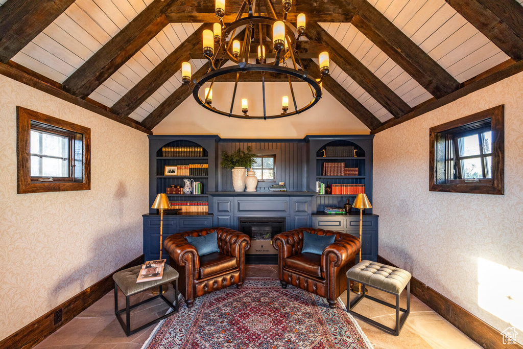 Living area with built in shelves, a notable chandelier, and vaulted ceiling with beams