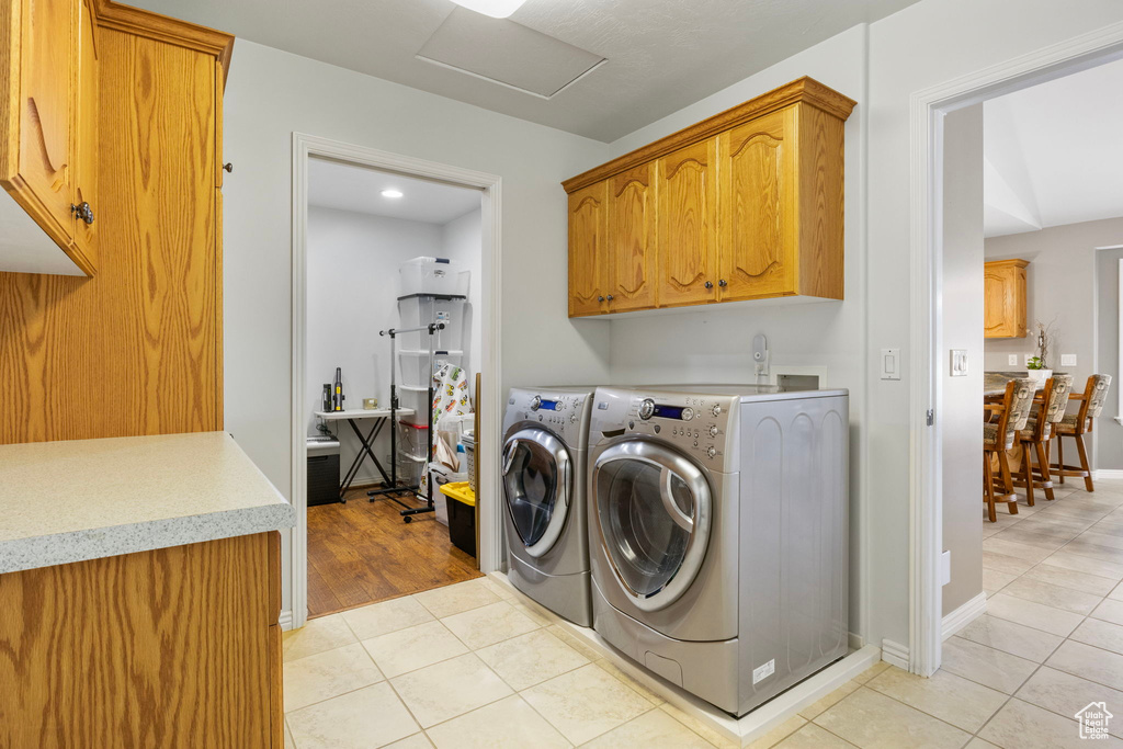 Laundry area featuring washer and clothes dryer, cabinets, and light hardwood / wood-style flooring